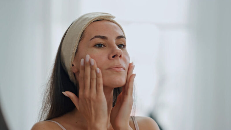 The woman applies face cream as part of her self-care routine