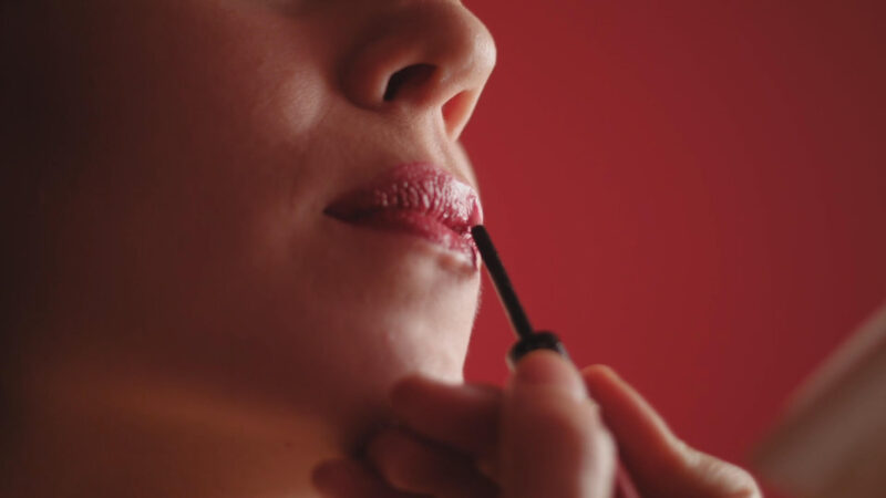 Woman putting on lipstick