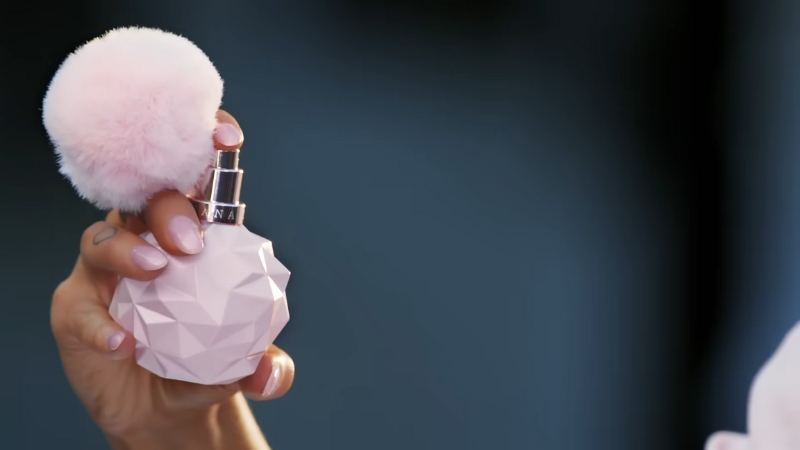 A hand holds the pink, faceted bottle of Sweet Like Candy by Ariana Grande
