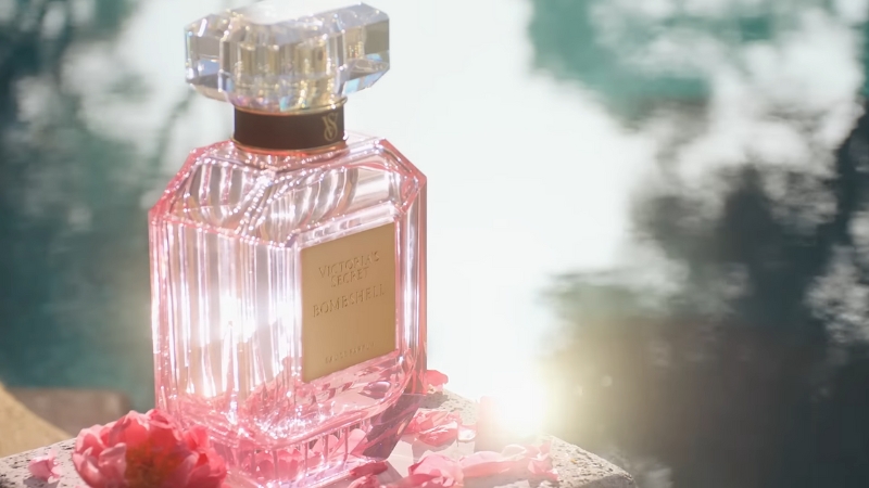 Victoria’s Secret Bombshell perfume bottle in pink glass sits by the water