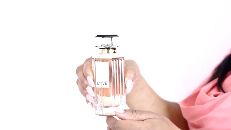 A woman holds a bottle of Victoria’s Secret Love perfume