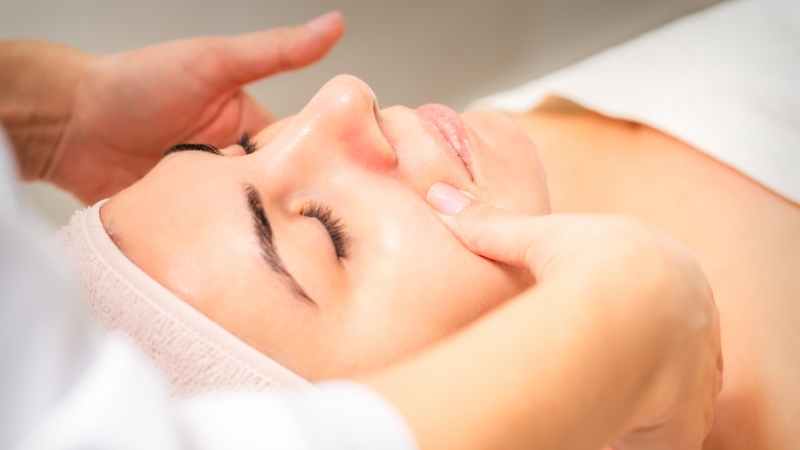 Close-up of a woman receiving a gentle facial lymphatic massage from a professional