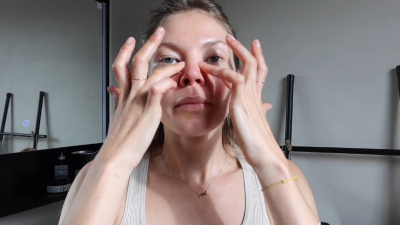 Woman massaging her face around the nose and cheeks as part of a facial lymphatic massage routine