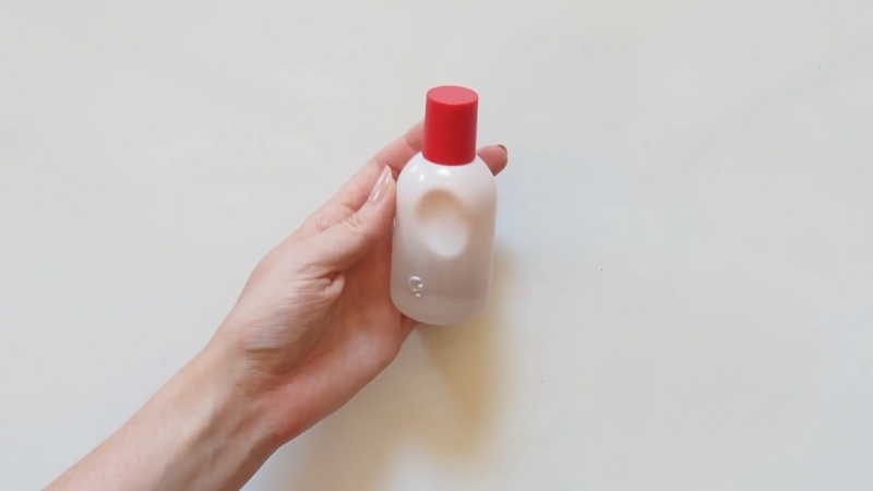 Glossier You Eau de Parfum bottle with a red cap held in hand against a plain background
