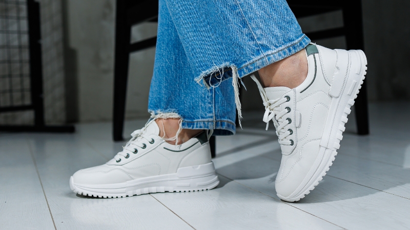 Close-up of white statement sneakers styled with frayed hem jeans as an affordable fashion choice