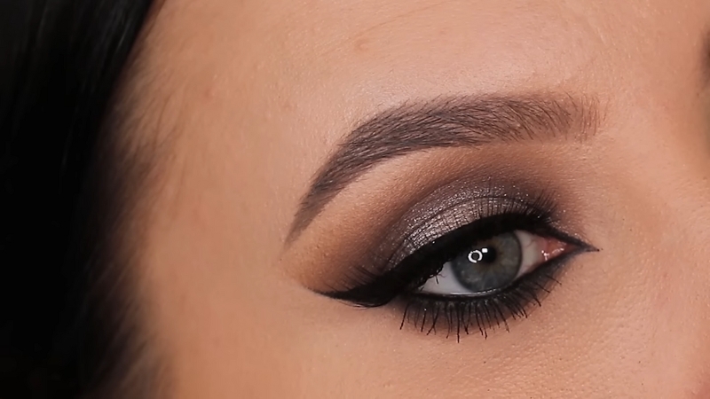 Close-up of an eye with metallic brown eyeshadow and precise black eyeliner