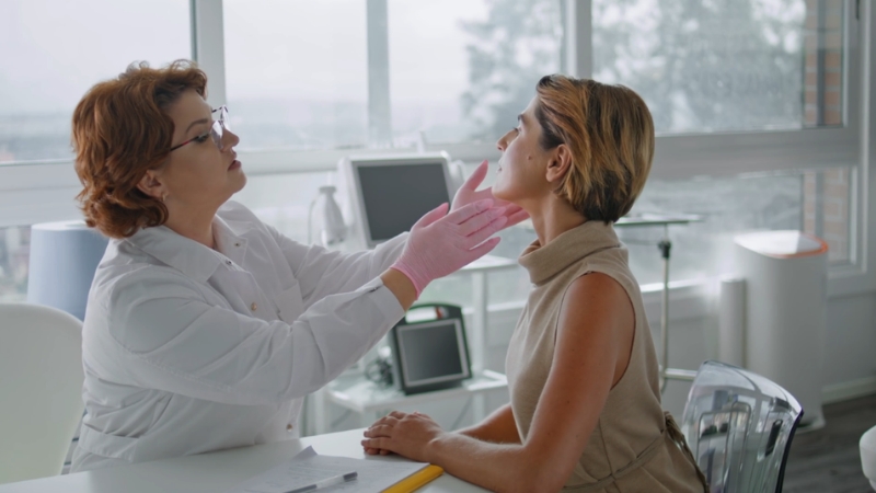 A dermatologist examines a woman’s skin during a consultation in a clinic