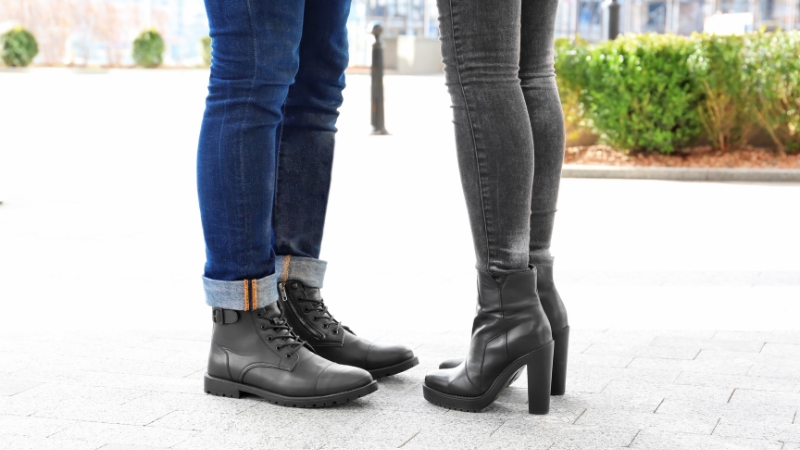 Close-up of a couple wearing coordinated black boots and dark denim on a city walkway