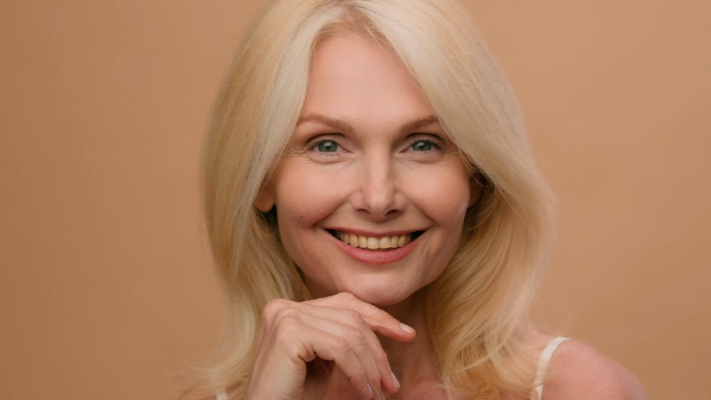 Mature woman touch skin after 30 days of anti-aging product use