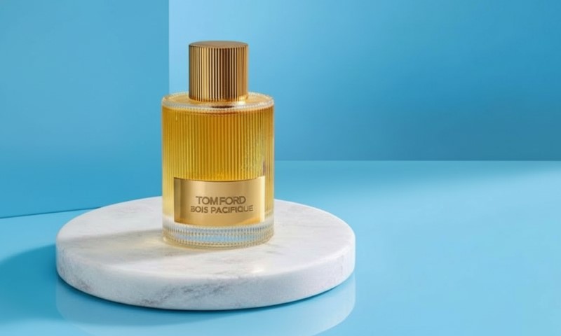 Tom Ford Bois Pacifique fragrance bottle on a white marble pedestal against a bright blue background