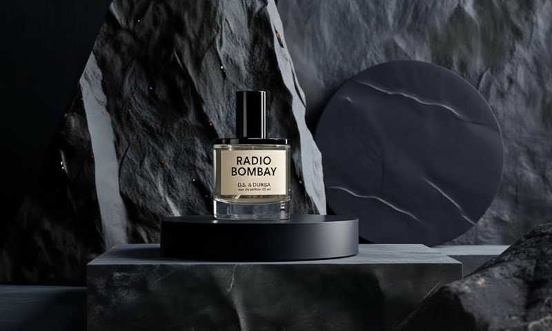 D.S. & Durga Radio Bombay perfume bottle resting on a dark marble pedestal against a dramatic, textured black rock backdrop