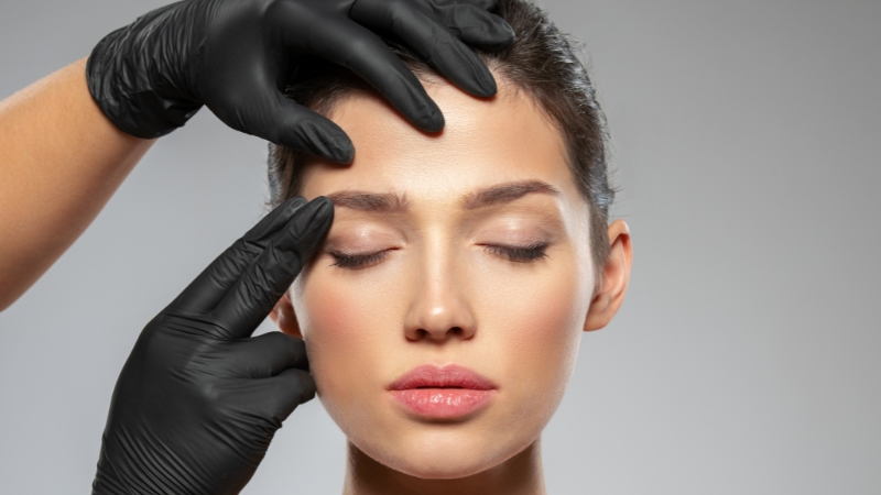 Professional assessing a woman’s face for rejuvenation treatment