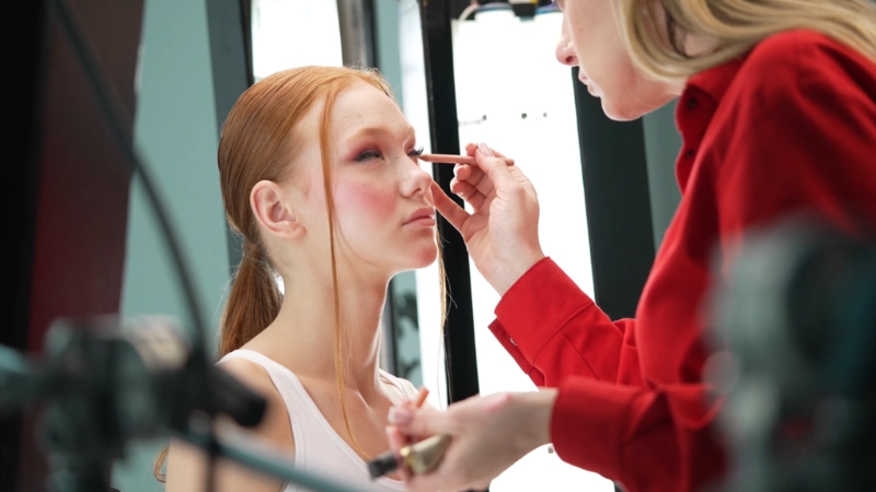 A makeup artist applying eyeshadow to a model during a studio session