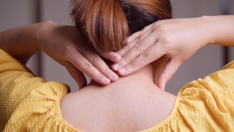 A person pressing their neck and shoulders, showing muscle tension caused by chronic stress
