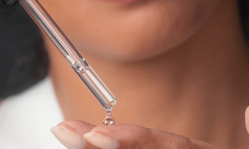 A woman holds a small glass tube filled with a colorful liquid