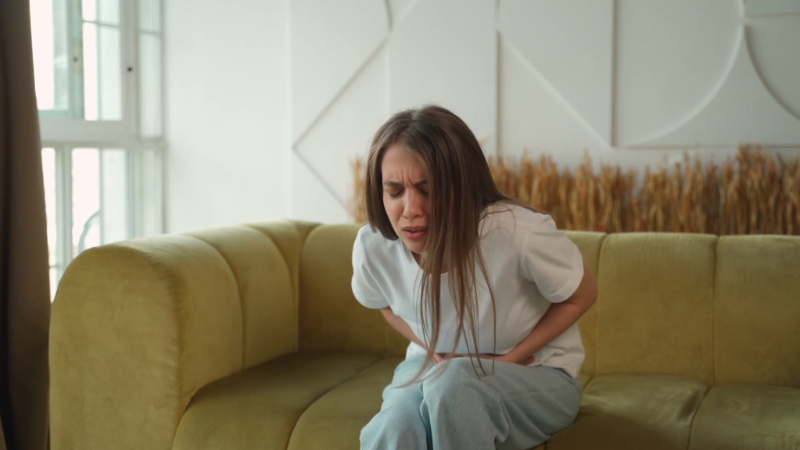 A woman holding her stomach in visible discomfort during a stress related gastrointestinal episode