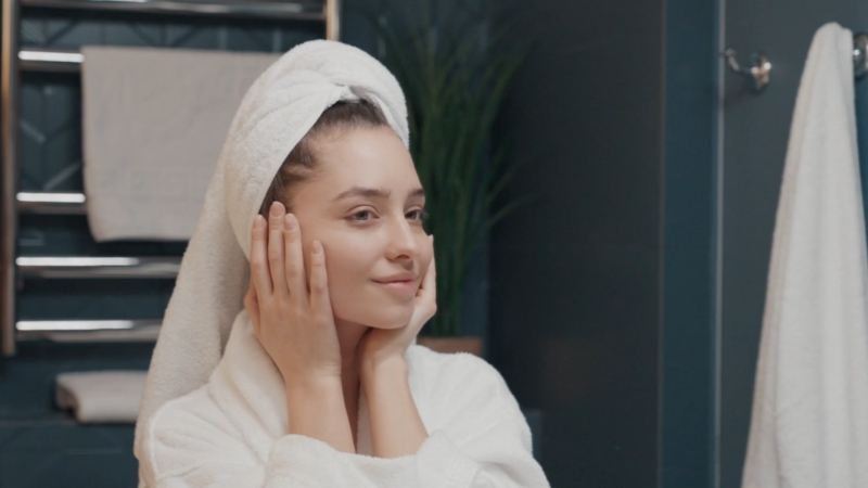 Woman gently patting her face after skincare in a bathroom