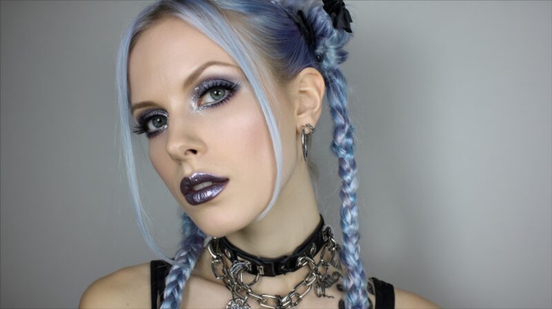 Model with blue braided hair wearing silver chrome eyeshadow and metallic purple lipstick