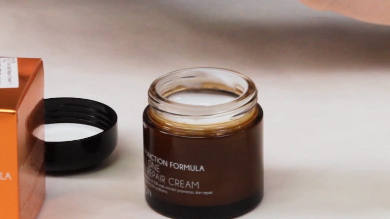 Open jar of Mizon Snail Repair Cream with lid beside the container on a table