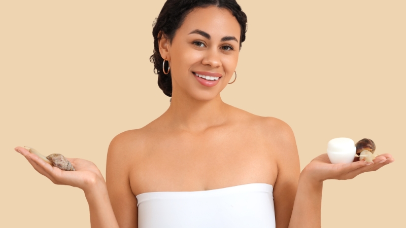 Woman holding a snail in one hand and a skincare cream jar in the other