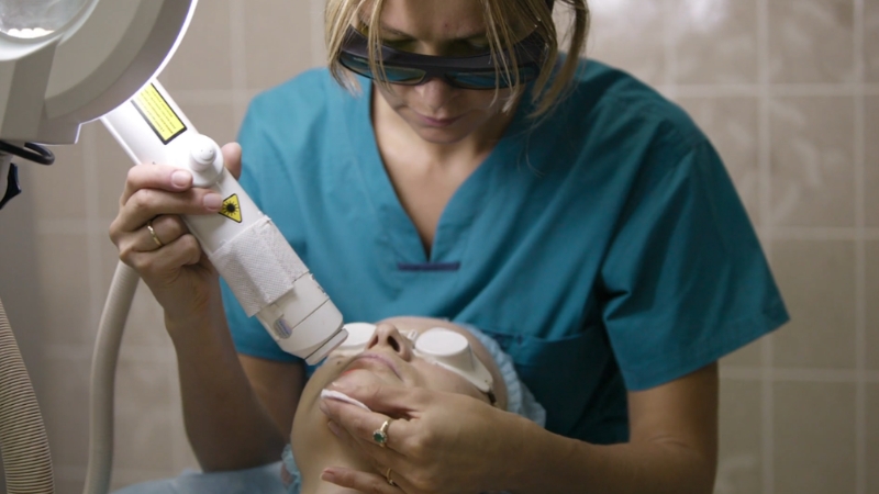 Clinician performing a laser facial treatment on a patient wearing protective eye shields