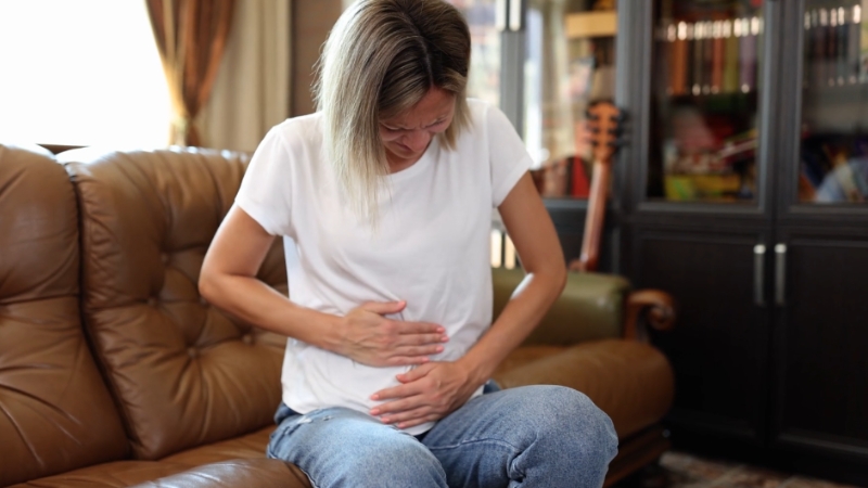 Woman holding her abdomen at home while recovering from laparoscopic ovarian cyst surgery pain