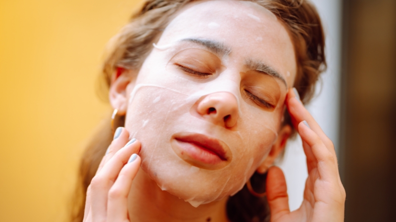 Woman applying a hydrating sheet mask as part of a treatment skincare routine