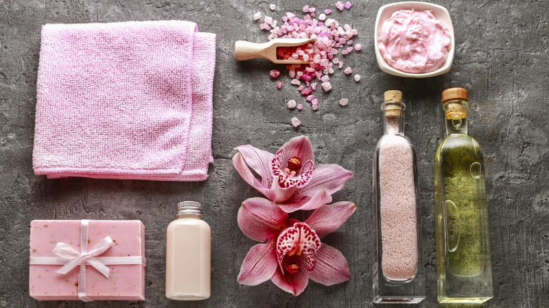 Pink spa wellness kit with towel, bath salts, oil, and soap arranged for a Women’s Day gift for mom