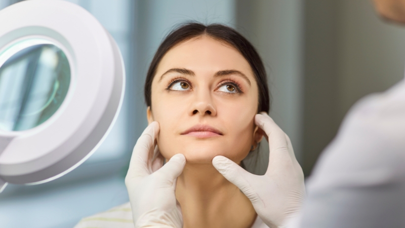 Dermatology skincare specialist examining a patient’s face during a skin consultation