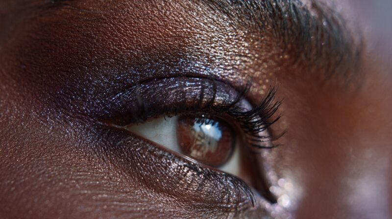 Close up of eye with deep shimmering eyeshadow on dark skin