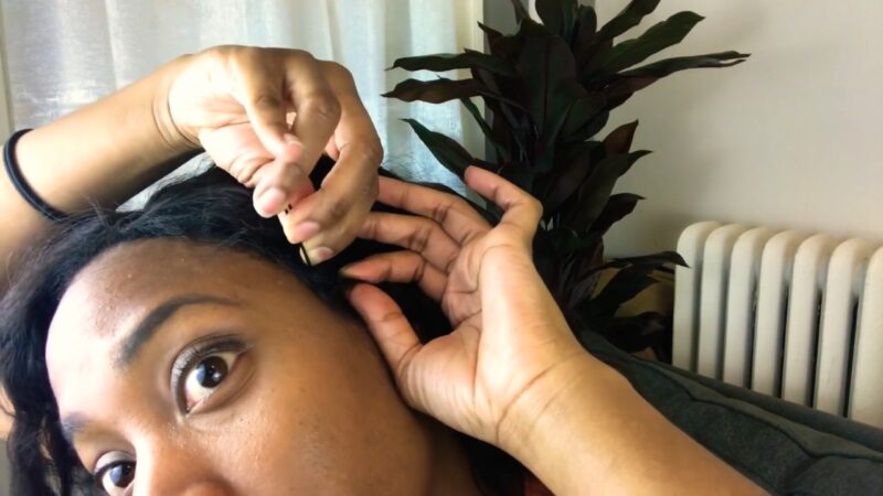 Woman secures her wig near the hairline with a bobby pin for extra hold