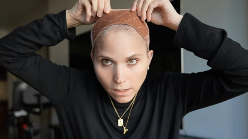 Woman places a wig grip on her head before putting on her wig