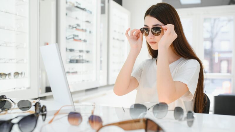 A woman tries on sunglasses in a bright eyewear store
