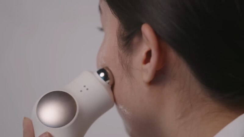 A woman uses a microcurrent device along her jawline