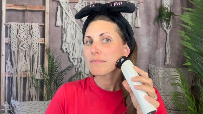 A woman uses a microcurrent device along her jawline